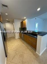 kitchen with recessed lighting, brown cabinetry, dark countertops, and refrigerator