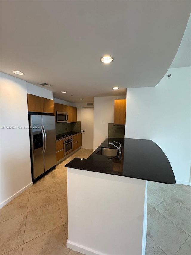 kitchen featuring recessed lighting, stainless steel appliances, a peninsula, a sink, and dark countertops