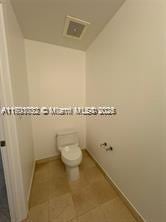 bathroom featuring toilet, tile patterned flooring, visible vents, and baseboards