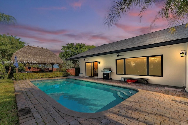 pool at dusk featuring a gazebo, a patio area, and area for grilling