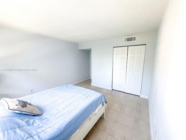 bedroom featuring light tile patterned floors, a textured ceiling, and a closet