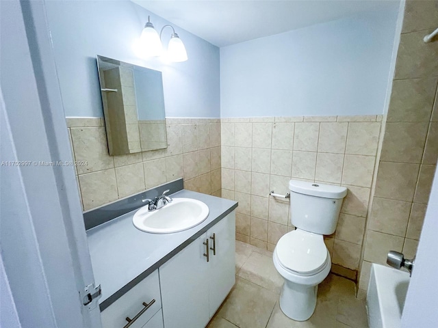 bathroom with vanity, a bathing tub, tile patterned flooring, toilet, and tile walls