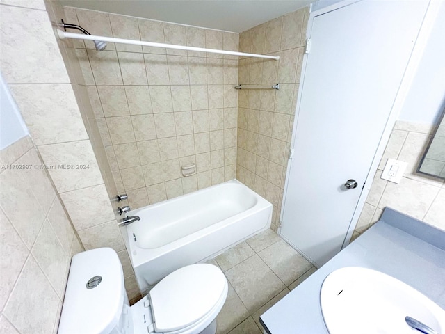 full bathroom featuring vanity, tile patterned flooring, tiled shower / bath combo, toilet, and tile walls