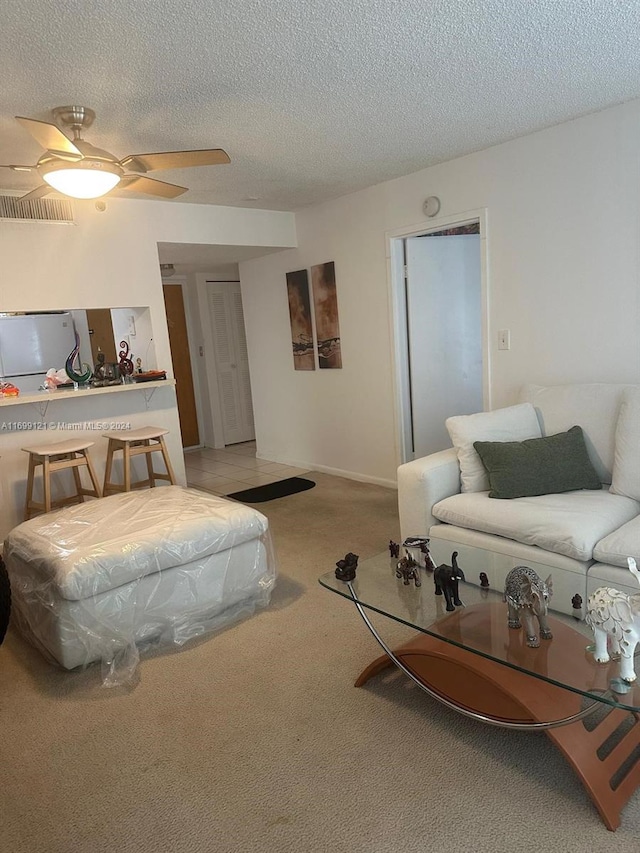 bedroom with a textured ceiling, refrigerator, light colored carpet, and ceiling fan