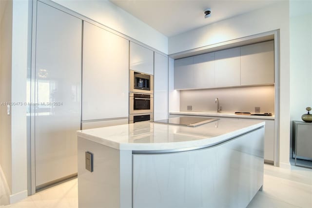 kitchen with black electric stovetop, a kitchen island, stainless steel microwave, and sink