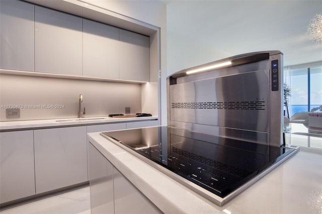 kitchen with black electric cooktop, white cabinetry, and sink