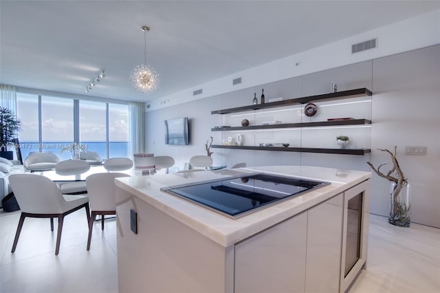 kitchen with pendant lighting, a kitchen island, black electric cooktop, and a chandelier