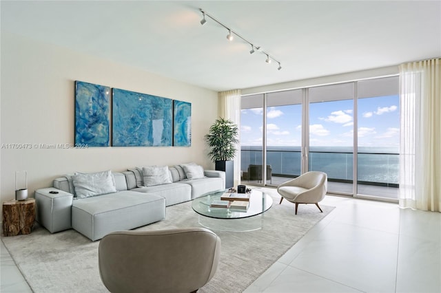 tiled living room with rail lighting, a water view, and a wall of windows