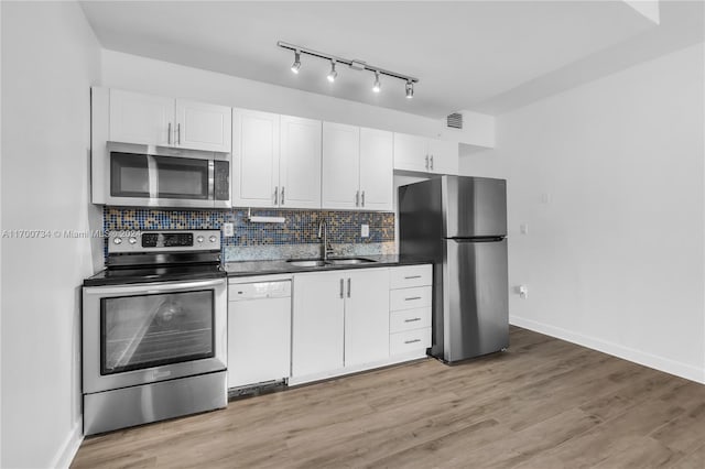 kitchen featuring sink, appliances with stainless steel finishes, decorative backsplash, white cabinets, and light wood-type flooring