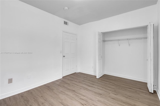 unfurnished bedroom featuring wood-type flooring and a closet