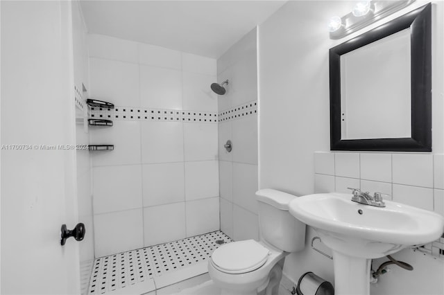 bathroom featuring tile patterned flooring, toilet, tiled shower, decorative backsplash, and tile walls