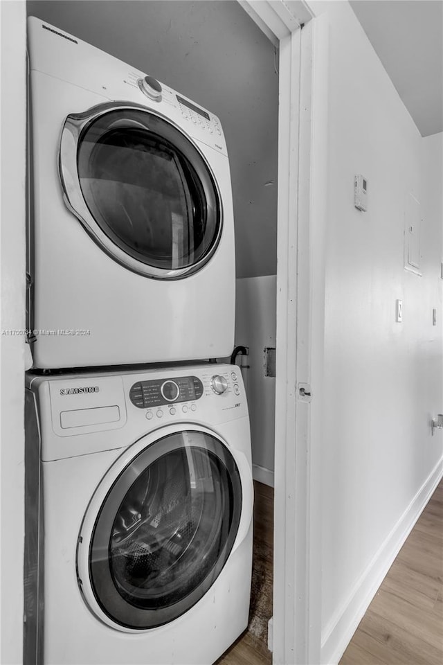 washroom with stacked washing maching and dryer and light hardwood / wood-style floors