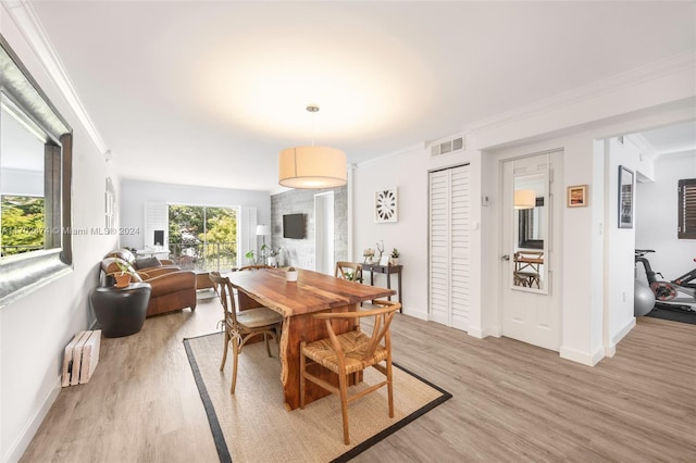 dining space featuring light wood-type flooring, radiator heating unit, and crown molding