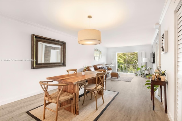 dining room featuring light wood-type flooring and crown molding