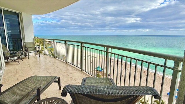 balcony featuring a view of the beach and a water view