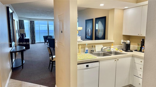 kitchen featuring white cabinetry, dishwasher, sink, a wall of windows, and light carpet