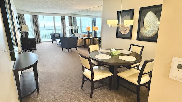 dining room with a water view, a textured ceiling, and a wall of windows