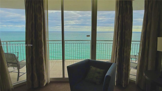 interior space with dark colored carpet, a water view, and a wealth of natural light