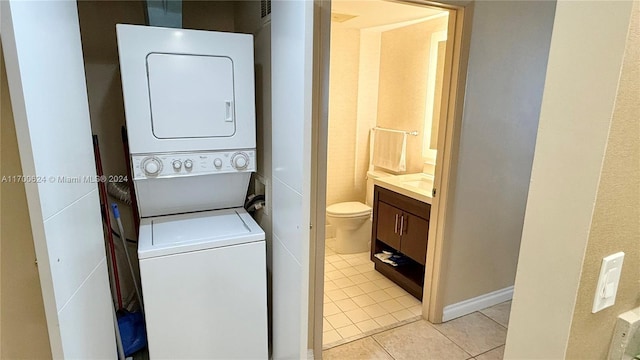 laundry room featuring light tile patterned flooring and stacked washer / dryer