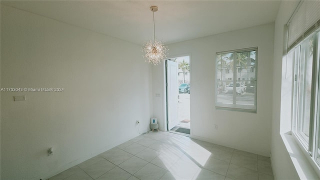 unfurnished room with light tile patterned floors and an inviting chandelier