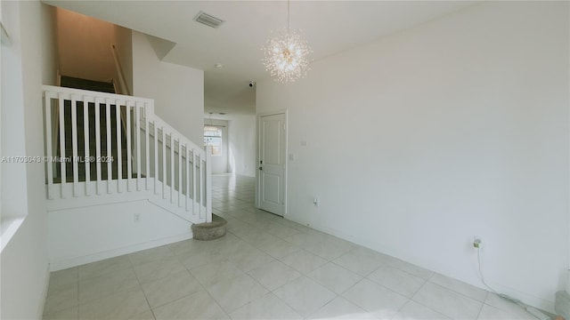 tiled spare room featuring a chandelier