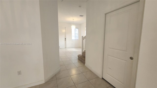 hall with light tile patterned floors and an inviting chandelier