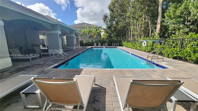 view of swimming pool featuring ceiling fan and a patio