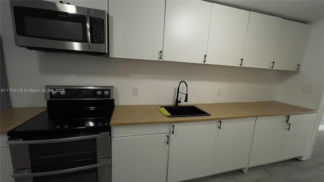 kitchen with sink, range with two ovens, and white cabinetry