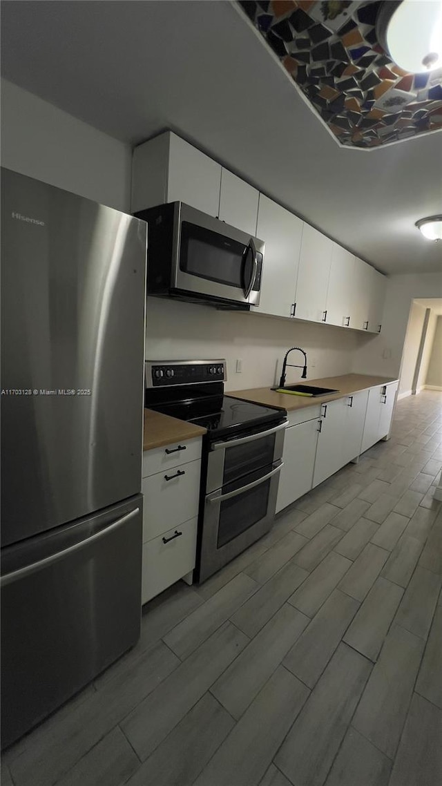 kitchen featuring stainless steel appliances, white cabinets, and sink