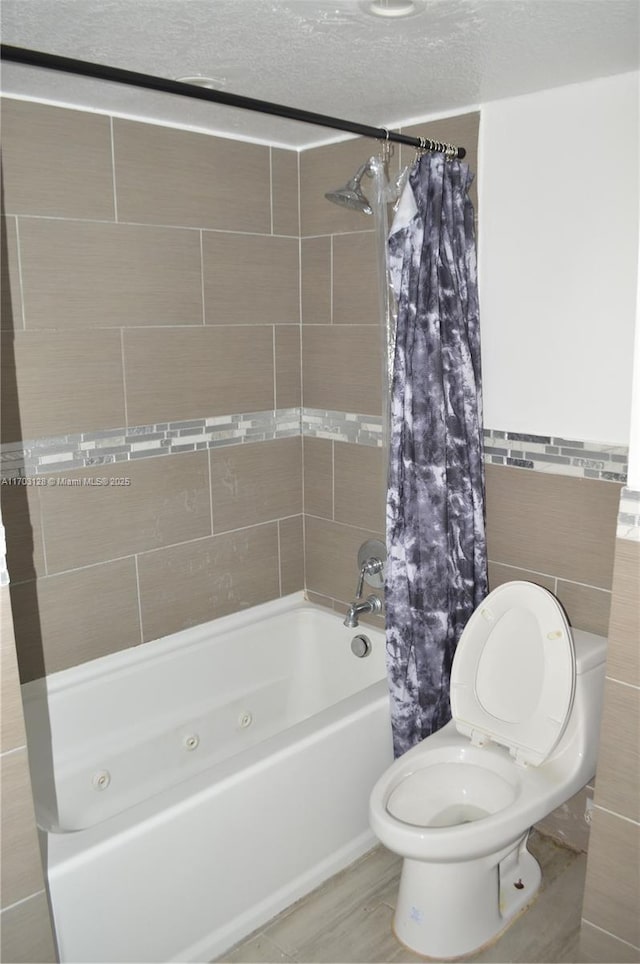 bathroom featuring toilet, tile walls, shower / bath combo with shower curtain, and a textured ceiling