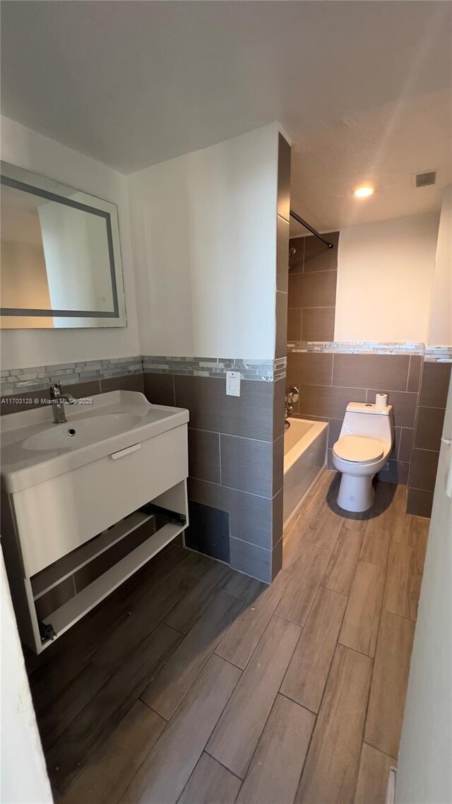 unfurnished bedroom featuring ensuite bathroom, a barn door, and light hardwood / wood-style flooring