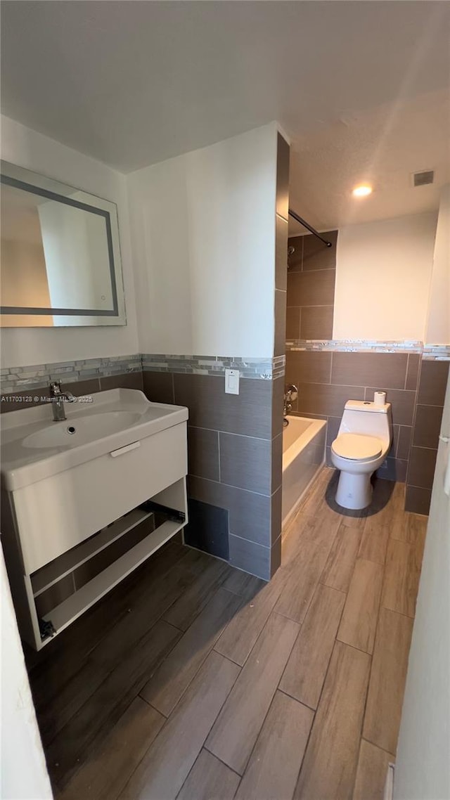 full bathroom featuring toilet, shower / bath combination, tile walls, and vanity