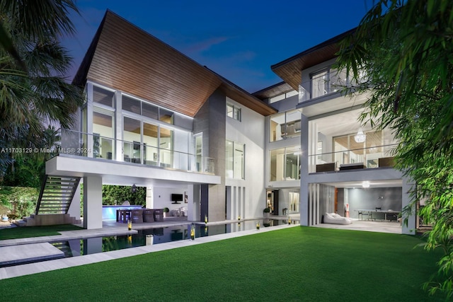 back of house with a lawn, a patio area, a balcony, and exterior kitchen