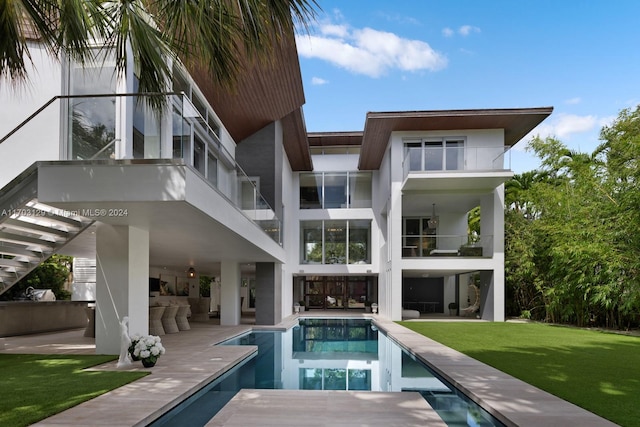 back of house with a lawn, an outdoor living space with a fireplace, a patio area, and a balcony