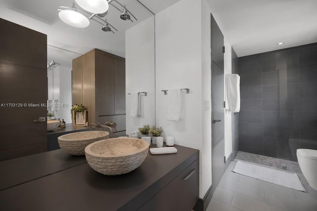 bathroom featuring tile patterned floors, vanity, a shower, tile walls, and toilet