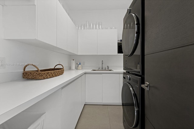 kitchen featuring sink, white cabinets, stacked washer and clothes dryer, and light tile patterned floors