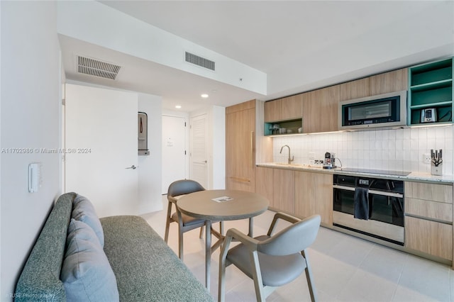 kitchen featuring appliances with stainless steel finishes, tasteful backsplash, and light brown cabinetry