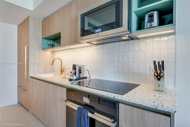 kitchen featuring decorative backsplash, light stone counters, sink, and stainless steel appliances