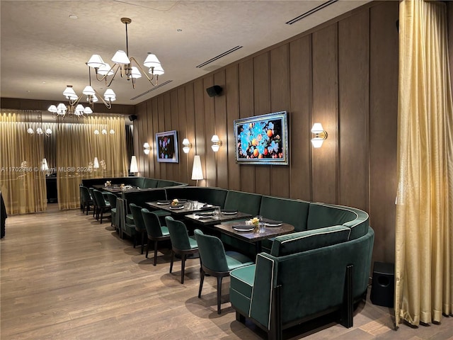 interior space featuring hardwood / wood-style floors, a notable chandelier, a textured ceiling, and wooden walls