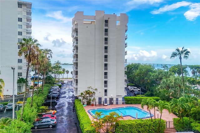 view of building exterior with a water view and a community pool