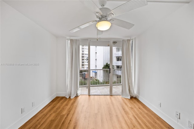 empty room featuring light hardwood / wood-style flooring, expansive windows, and ceiling fan