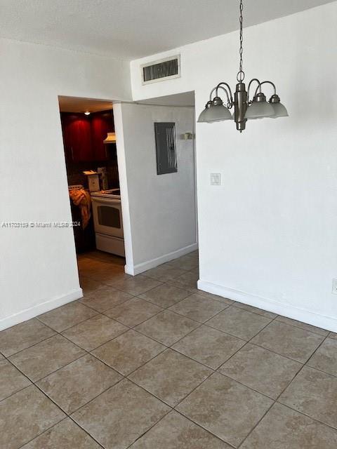 unfurnished dining area featuring tile patterned floors, electric panel, and an inviting chandelier