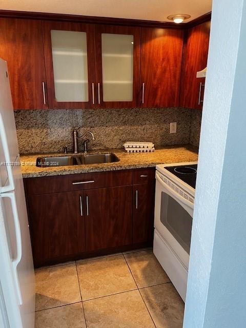 kitchen featuring light stone countertops, tasteful backsplash, white appliances, sink, and light tile patterned floors