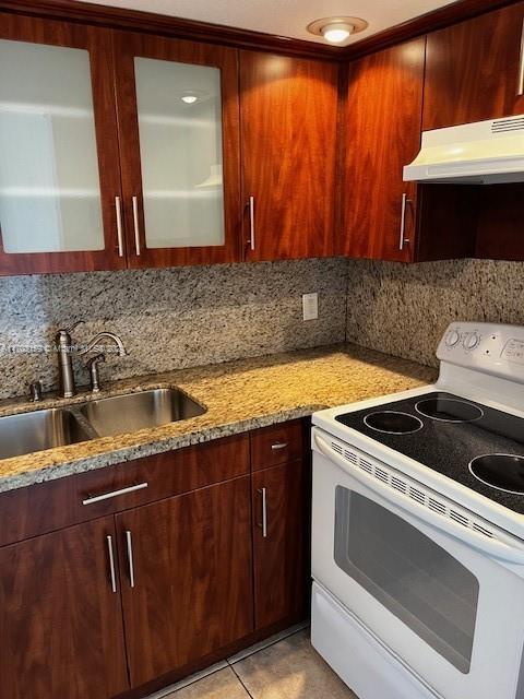 kitchen with electric range, sink, light stone countertops, tasteful backsplash, and light tile patterned floors