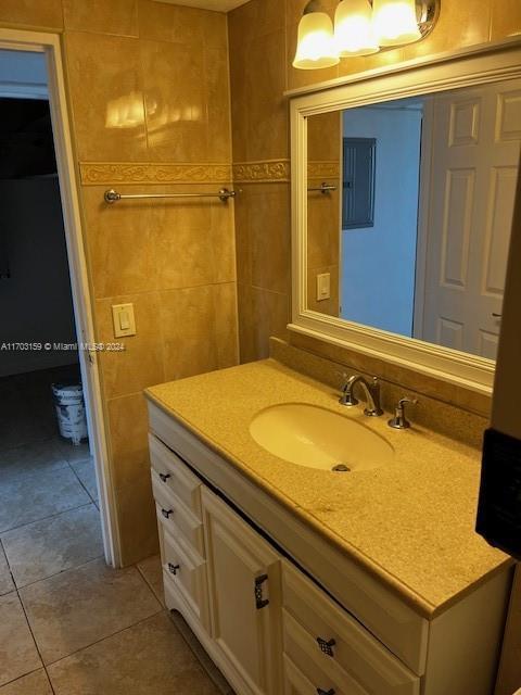 bathroom featuring tile patterned flooring, vanity, and tile walls