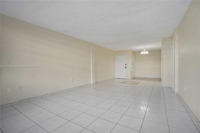 tiled empty room with a notable chandelier