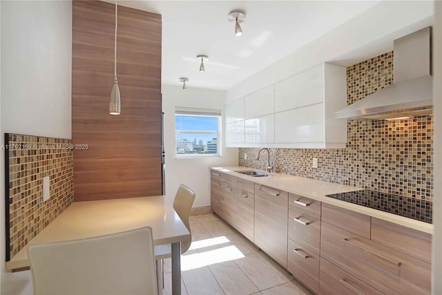 kitchen with sink, light tile patterned floors, wall chimney range hood, tasteful backsplash, and white cabinets