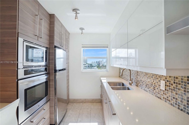 kitchen featuring backsplash, sink, light tile patterned floors, and stainless steel appliances