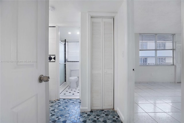 bathroom featuring tile patterned flooring, plenty of natural light, a shower with door, and toilet