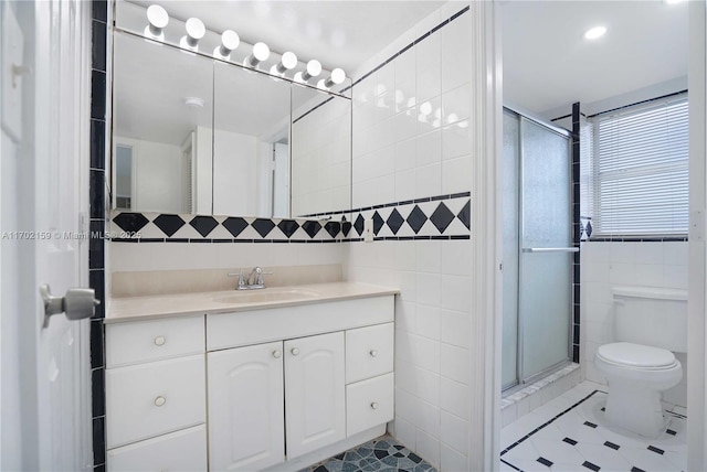 bathroom featuring tile patterned flooring, vanity, an enclosed shower, and tile walls